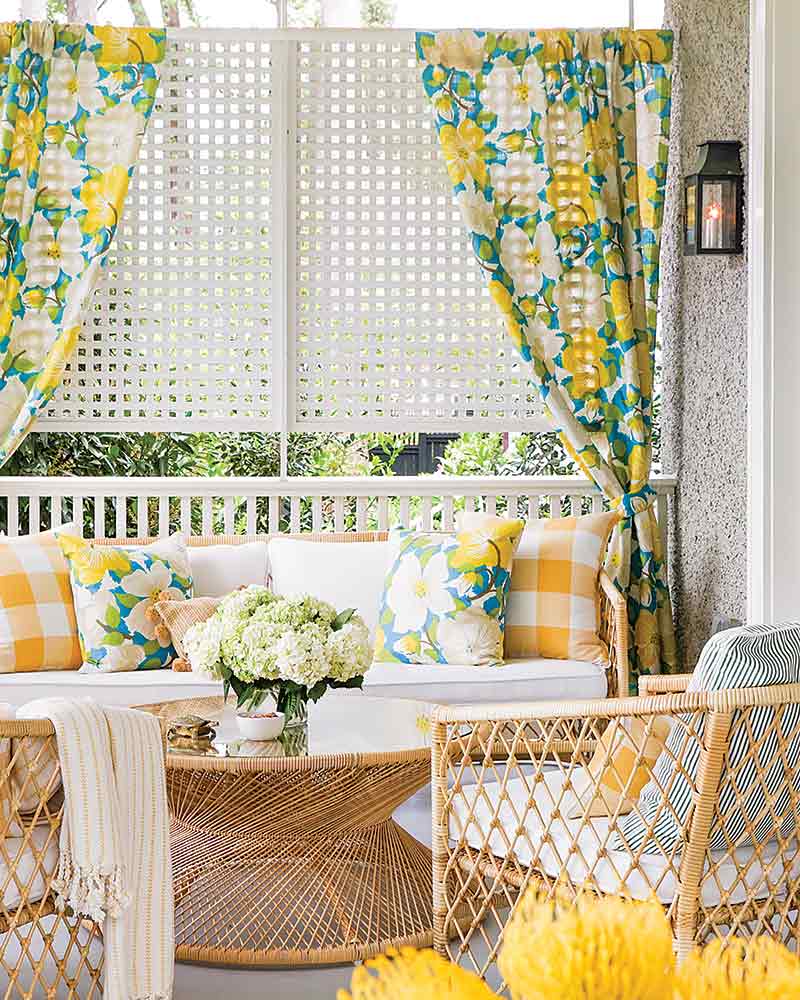A porch with wicker furniture and yellow, white, and green accents.