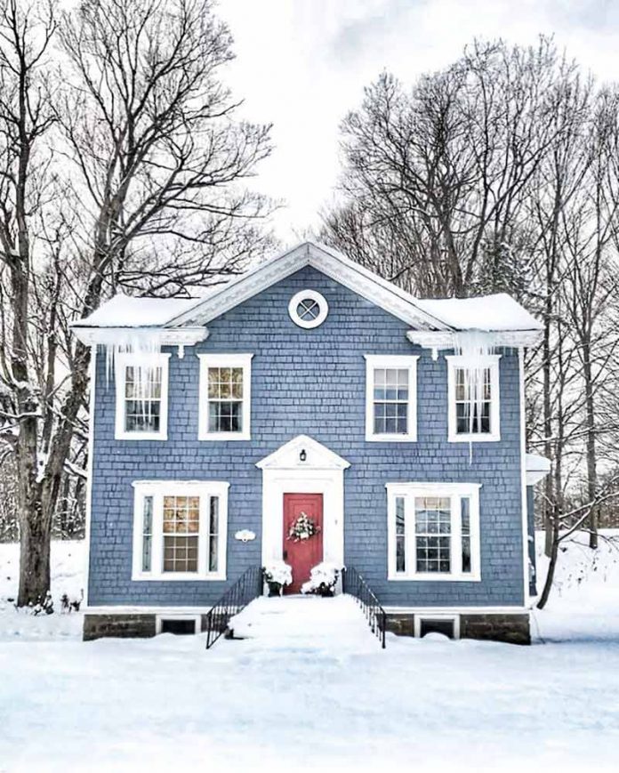 blue house with red front door in the snow