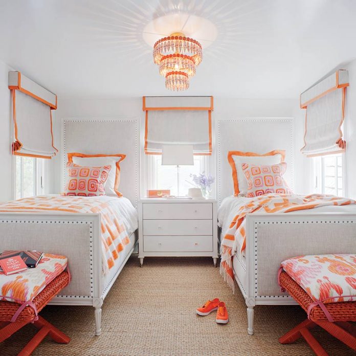white bedroom with bright orange accents and matching twin beds