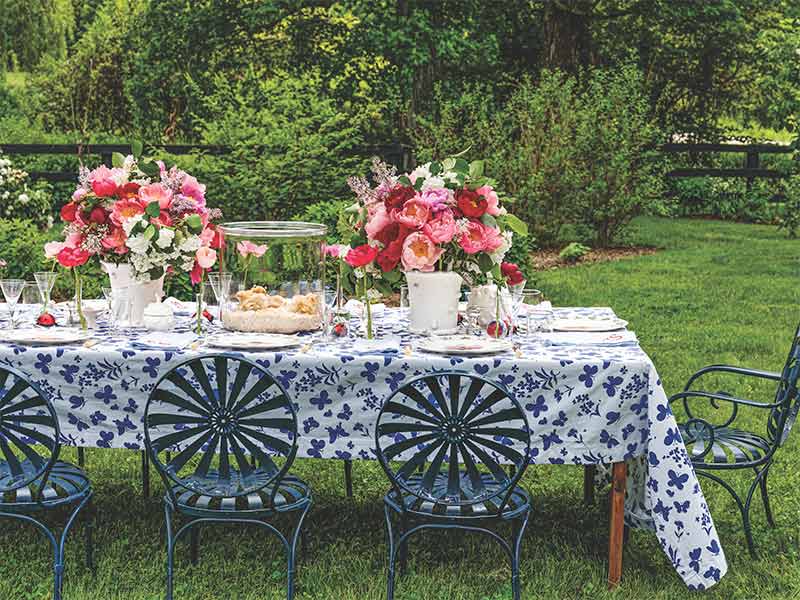 A spring alfresco tablescape with pink-and-red floral arrangements. 