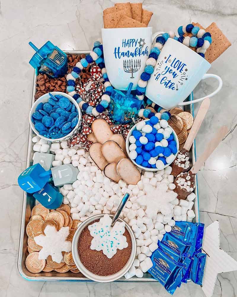 A Hanukkah-themed hot cocoa dessert board with blue and white candy. 