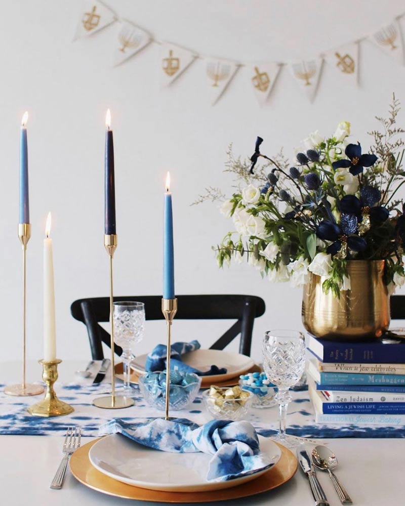 A modern Hanukkah-themed tablescape with blue, white, and gold accents. 