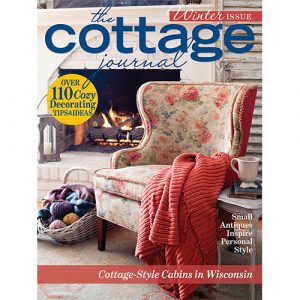 The Cottage Journal Winter 2022 Cover with fireplace, floral chair, and red blanket.