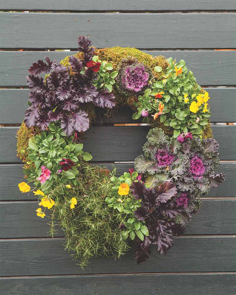 A wreath with purple vegetation and yellow flowers.