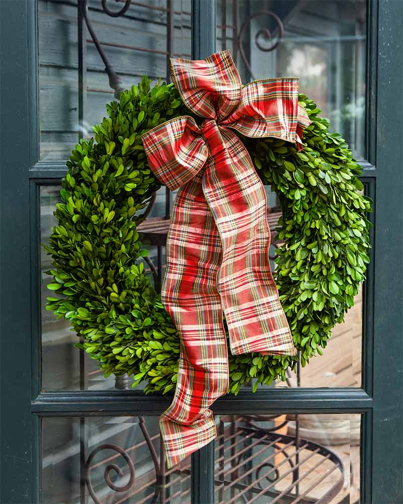 A boxwood wreath with a red plaid ribbon.