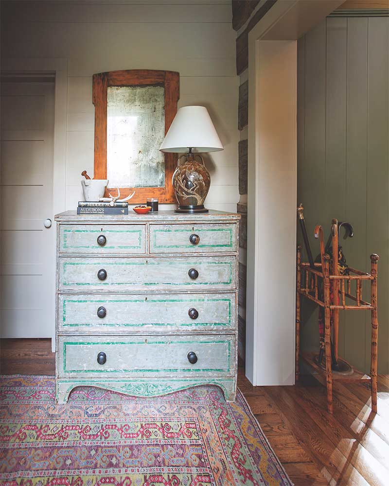 A weathered, blue dresser and an antique rug. 