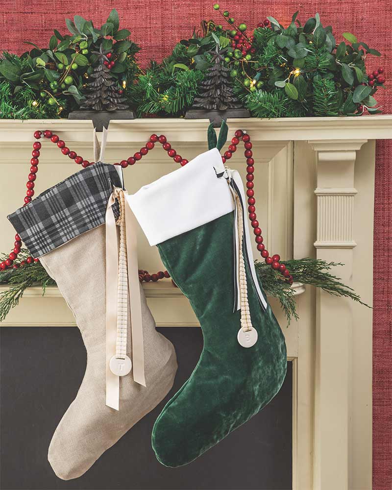 A mantle with two stockings, Christmas tree stocking holders, and a garland.