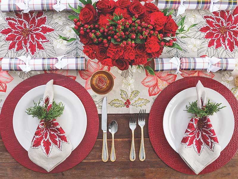 An overhead view of a poinsettia themed holiday tablescape. 