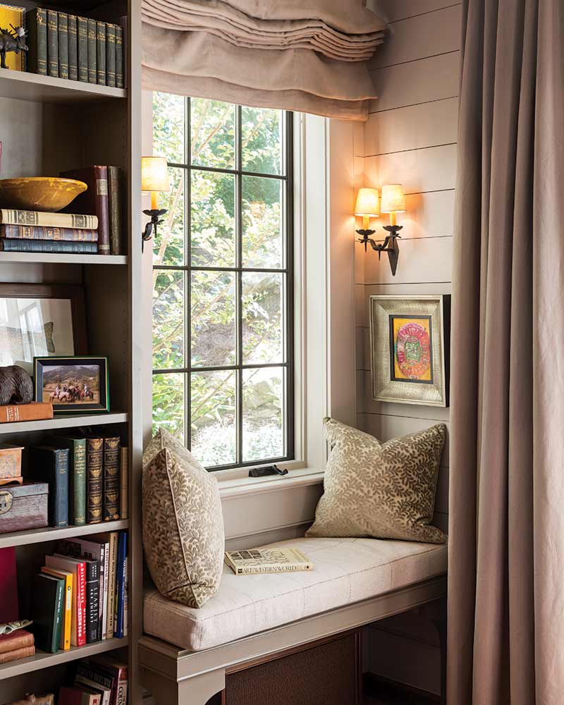 A window seat with cushions and a curtain. 