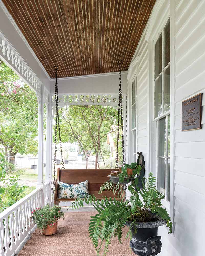 A porch swing on a wrap front porch.