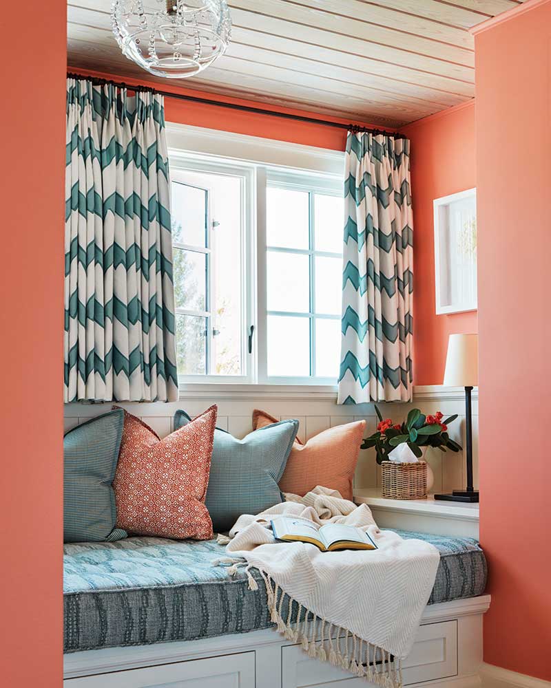 A window seat with aqua and coral accents. 