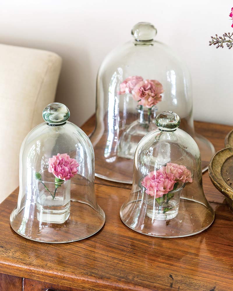 Miniature arrangements styled in bud vases underneath cloches.