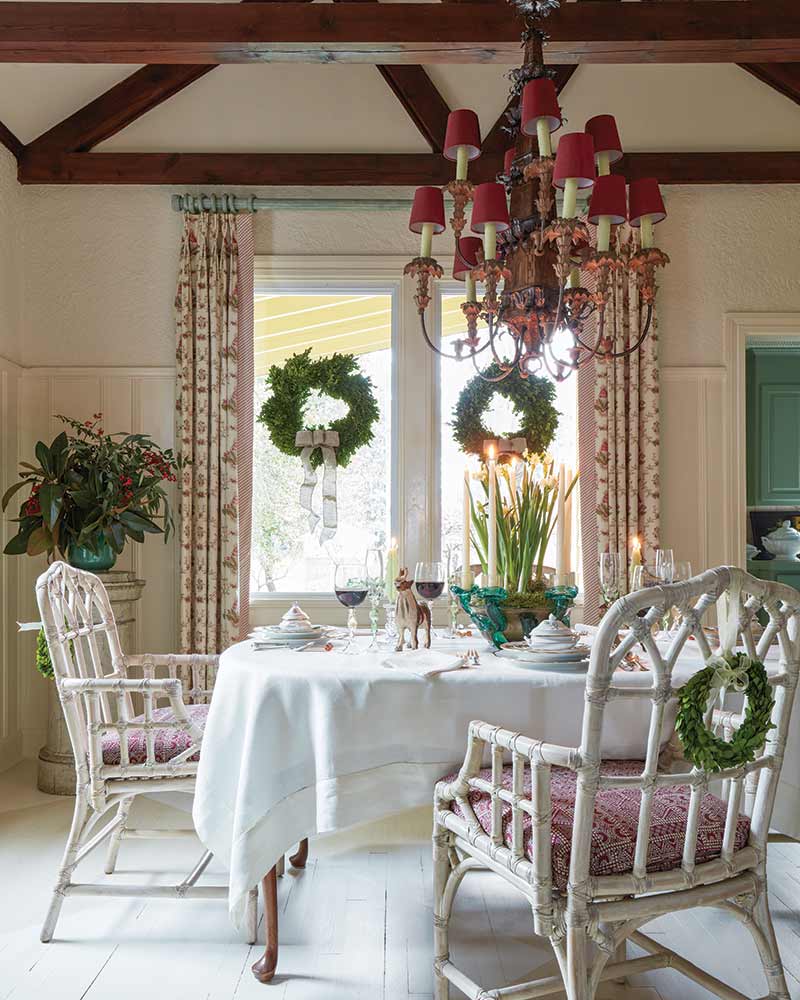 A dining room with white chippendale chairs and fresh wreaths.
