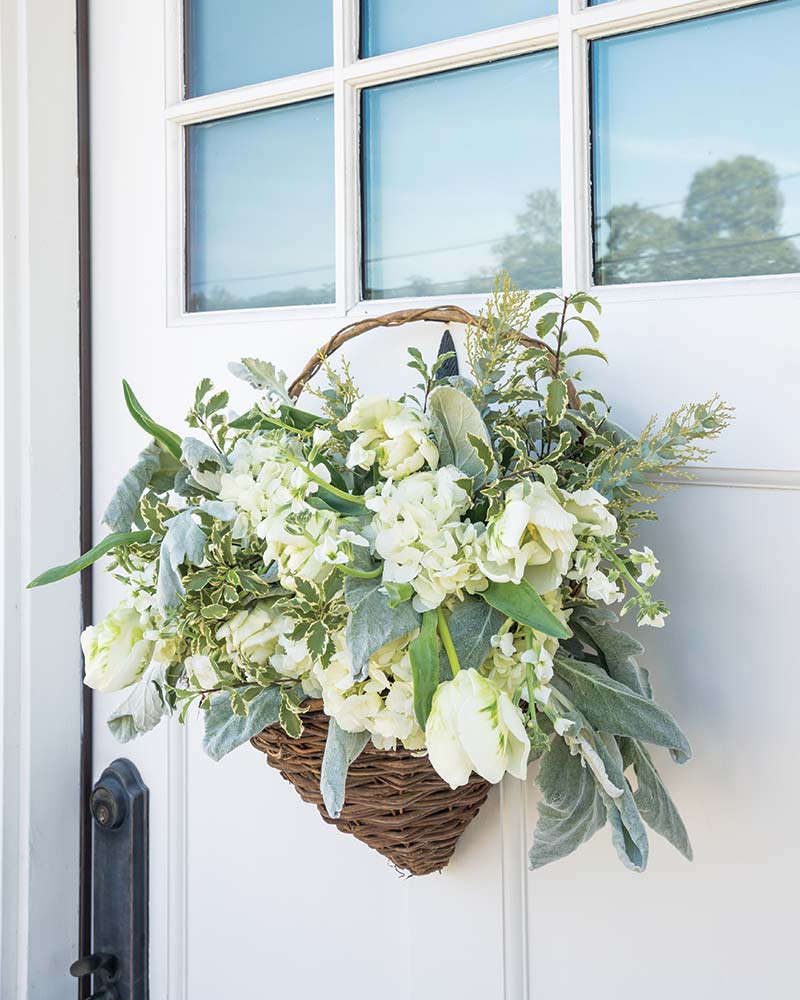 White blooms in a wicker basket door hanger.