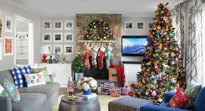 A living room with a tree and mantel decorated with colorful accents.