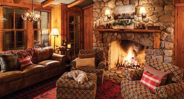 The living room in a cabin with a fireplace and a dog asleep on an ottoman.