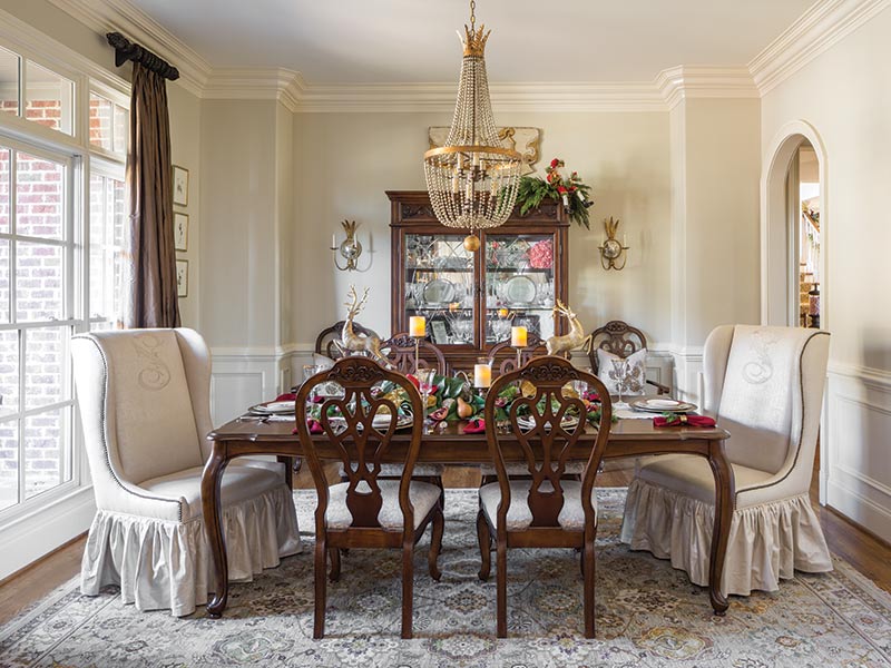 A formal dining room with dark wood furnishings and a chandelier. 