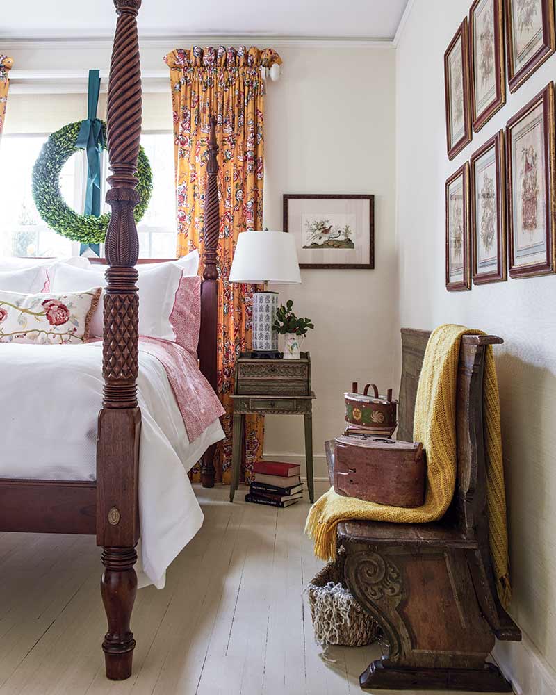 A guest bedroom with dark wood furnishings and bright orange accents.