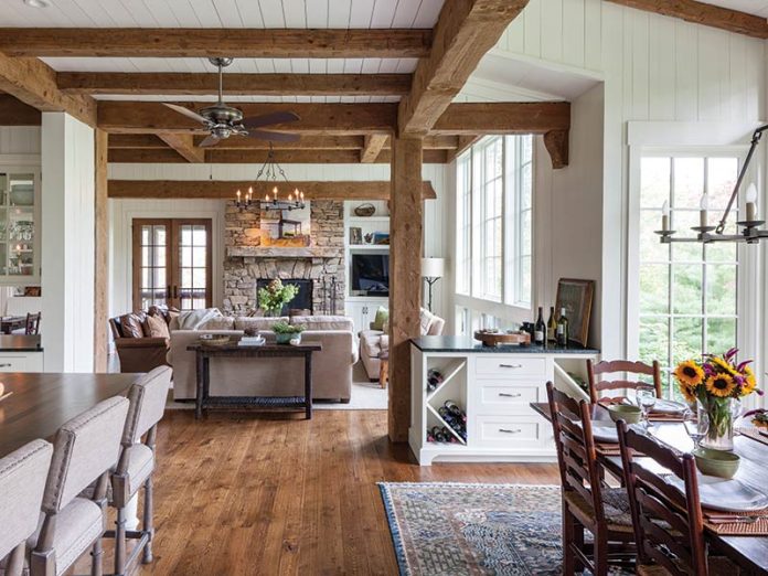 An open floor plan with white walls, hardwood floors, and wood beams.