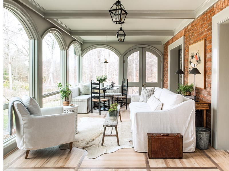 A sunroom with arched windows and sofas with white slip covers.