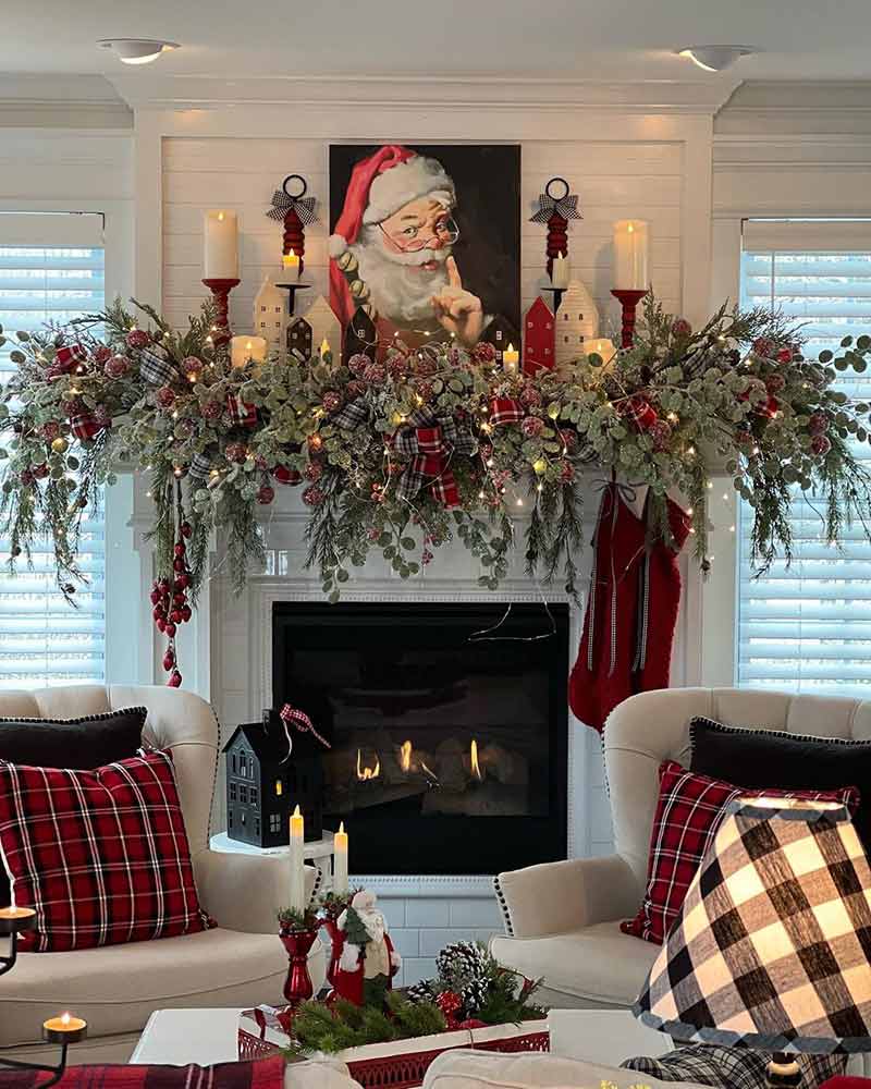 A mantel adorned with greenery and red berries. 