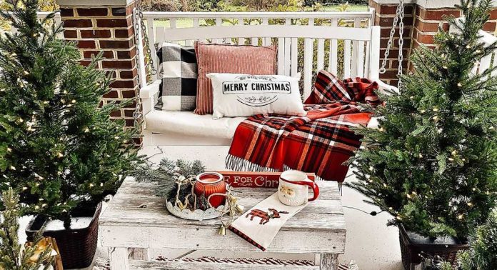 A porch swing with pillows and a plaid throw.