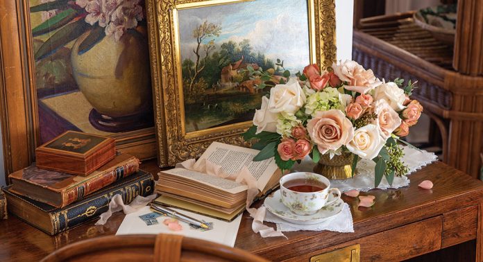 a tabletop vignette with tea, books, and roses.
