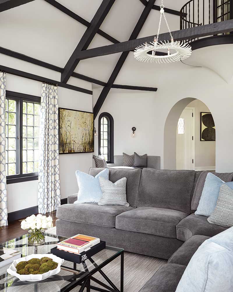 A living space with vaulted ceilings, wooden beams, and a grey sectional sofa.