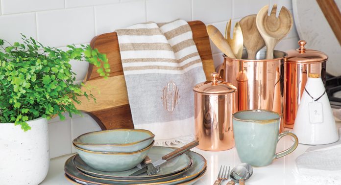 A kitchen counter with dishware and copper containers.