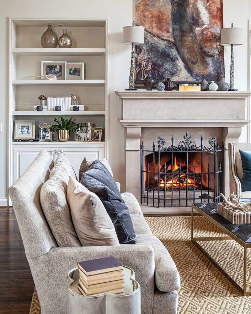 A living room with a fireplace, white furnishings, and abstract artwork.