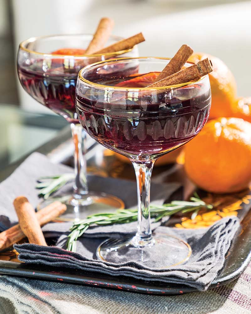 Two glasses of mulled wine garnished with cinnamon sticks.