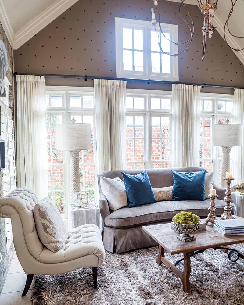 A sunroom with gray and white furnishings and blue accents.