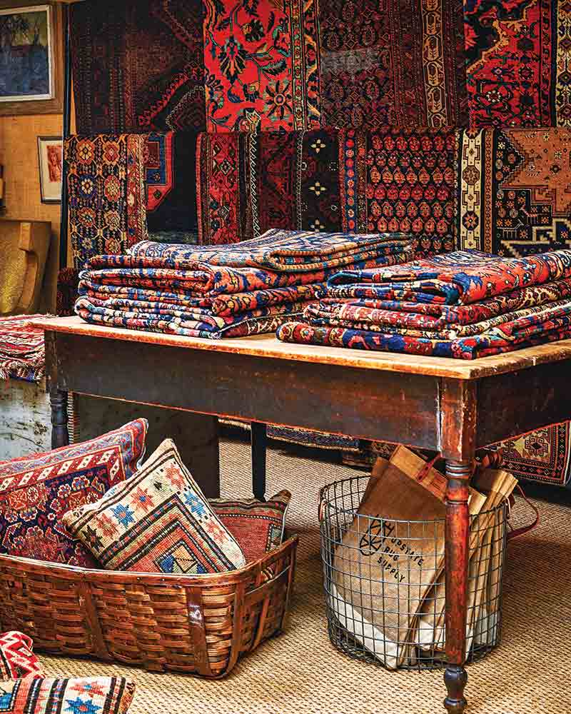 A table topped with folded antique rugs.