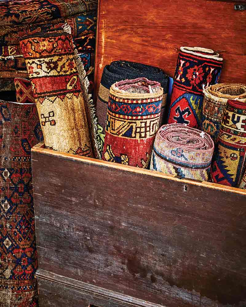 A trunk filled with antique rugs.