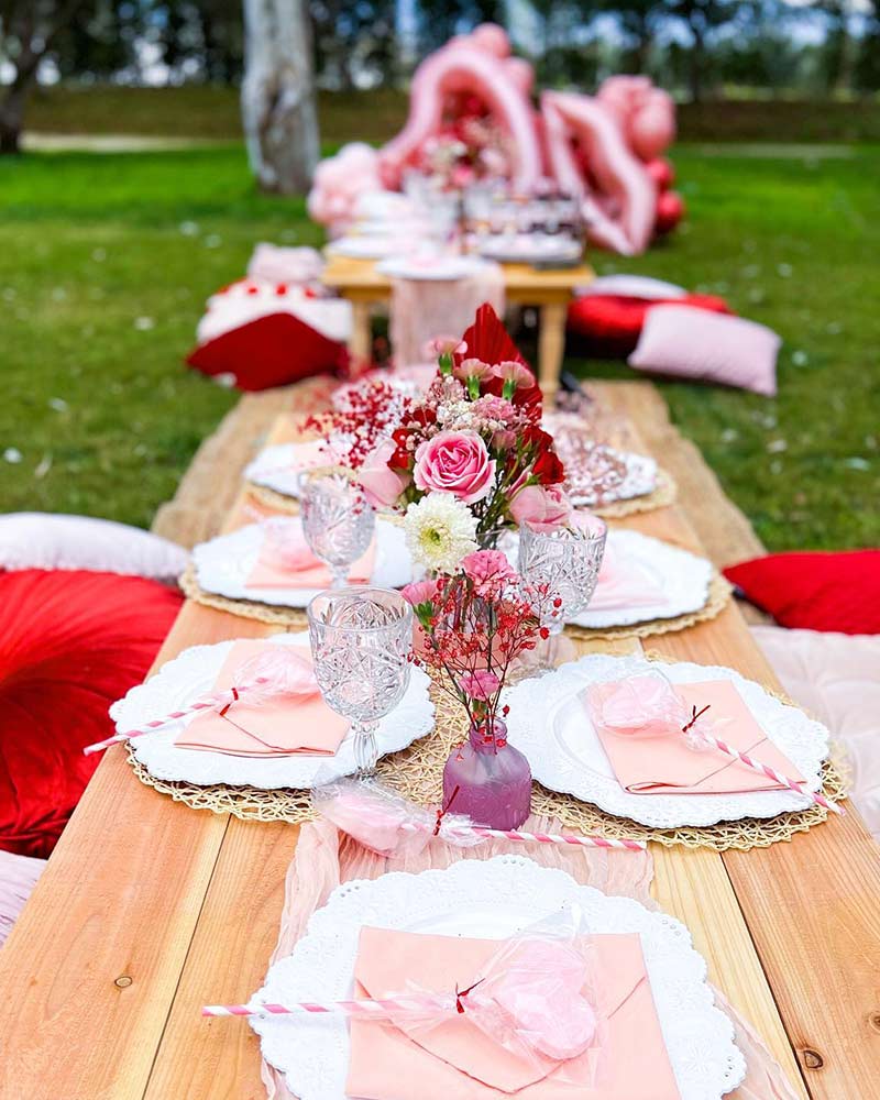 An outdoor setting with red and pink table accents and pilllows.