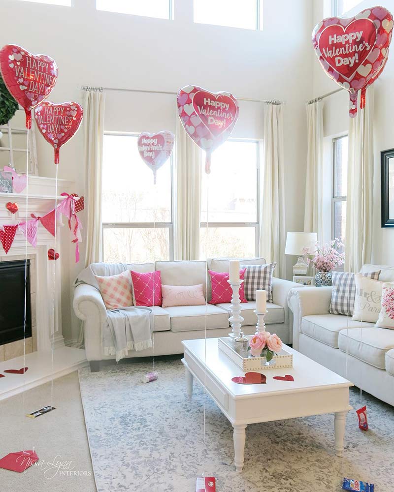 Red heart-shaped balloons in a living room with pink and red accessories