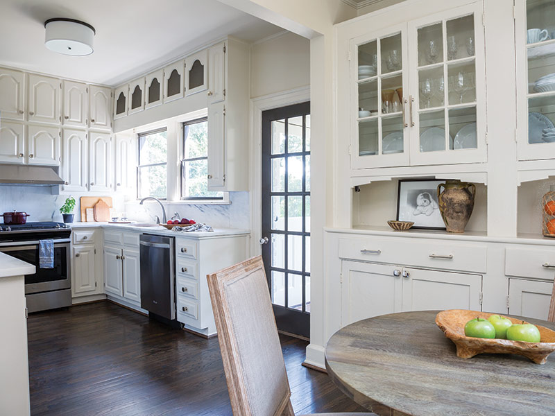 A white kitchen with dark hardwood floors.