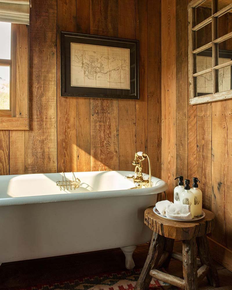 A clawfoot bathtub in a room with walls covered in wood panelling. 