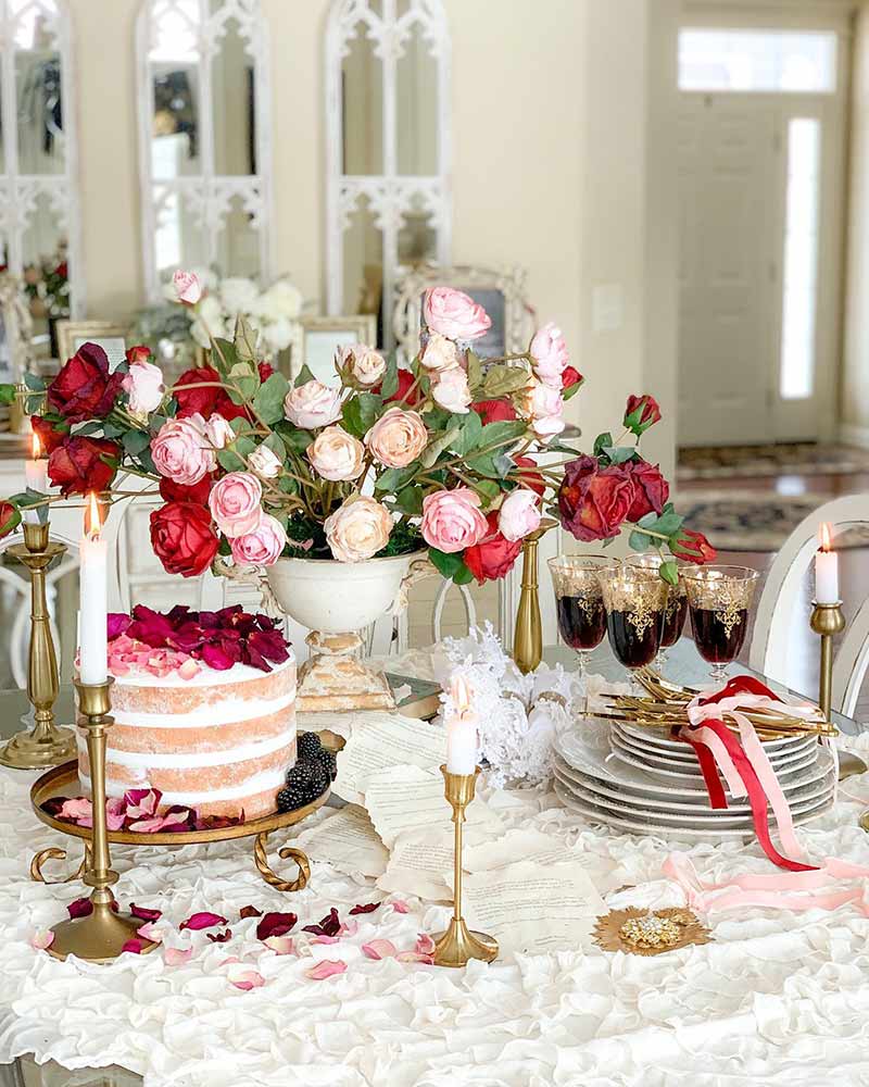 A Valentine's Day tablescape with roses, a cake, and candles.