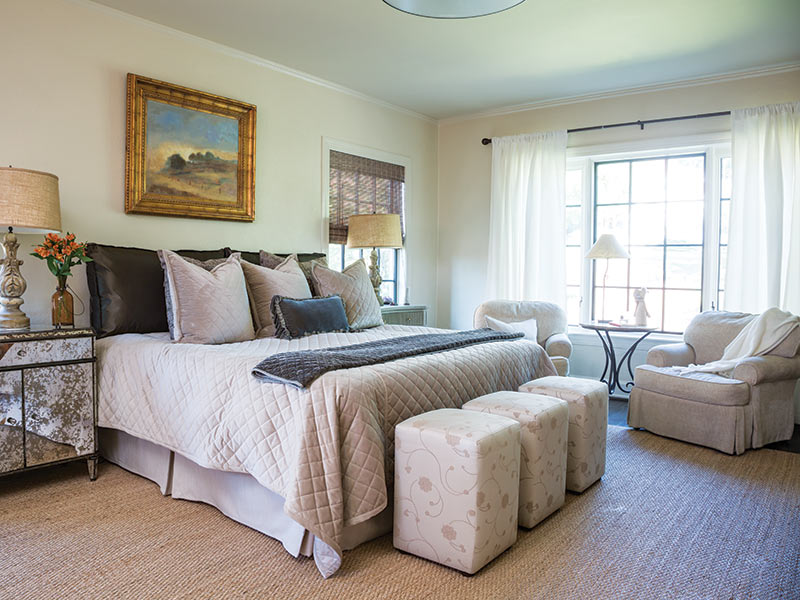 A bedroom with neutral furnishings and artwork.