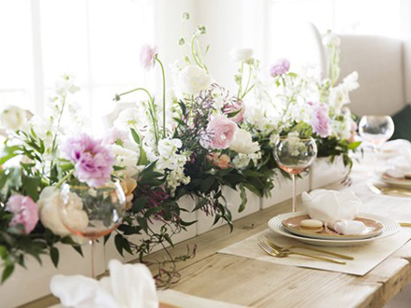 A long wooden box filled with flowers and used as a table runner.
