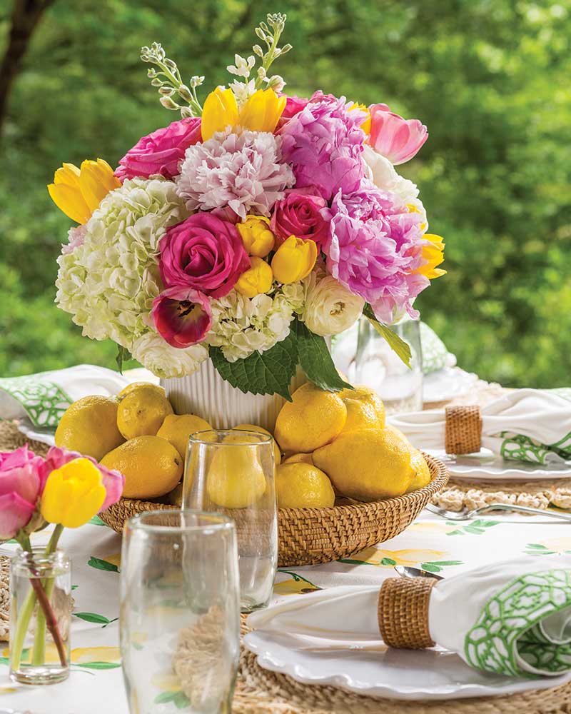 A floral centerpiece placed in a bowl of lemons.