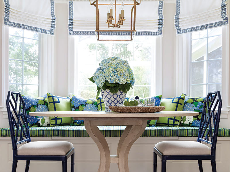 A breakfast nook built into a bay window and decorated with green and blue furnishings.