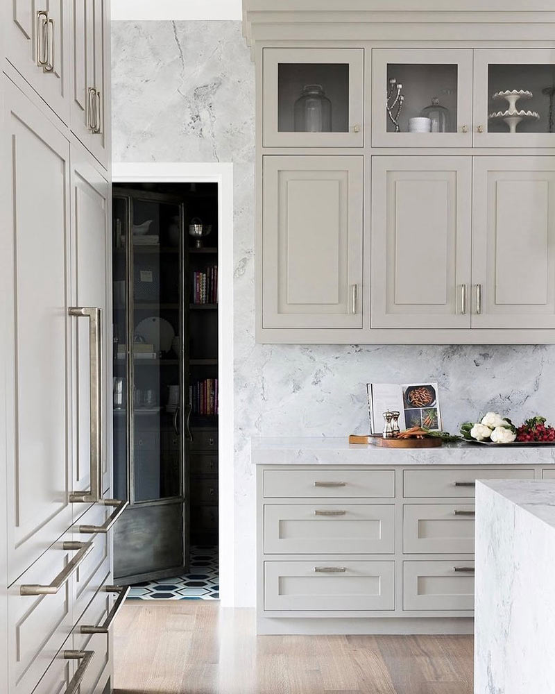 A white kitchen with silver oversize cabinet pulls.