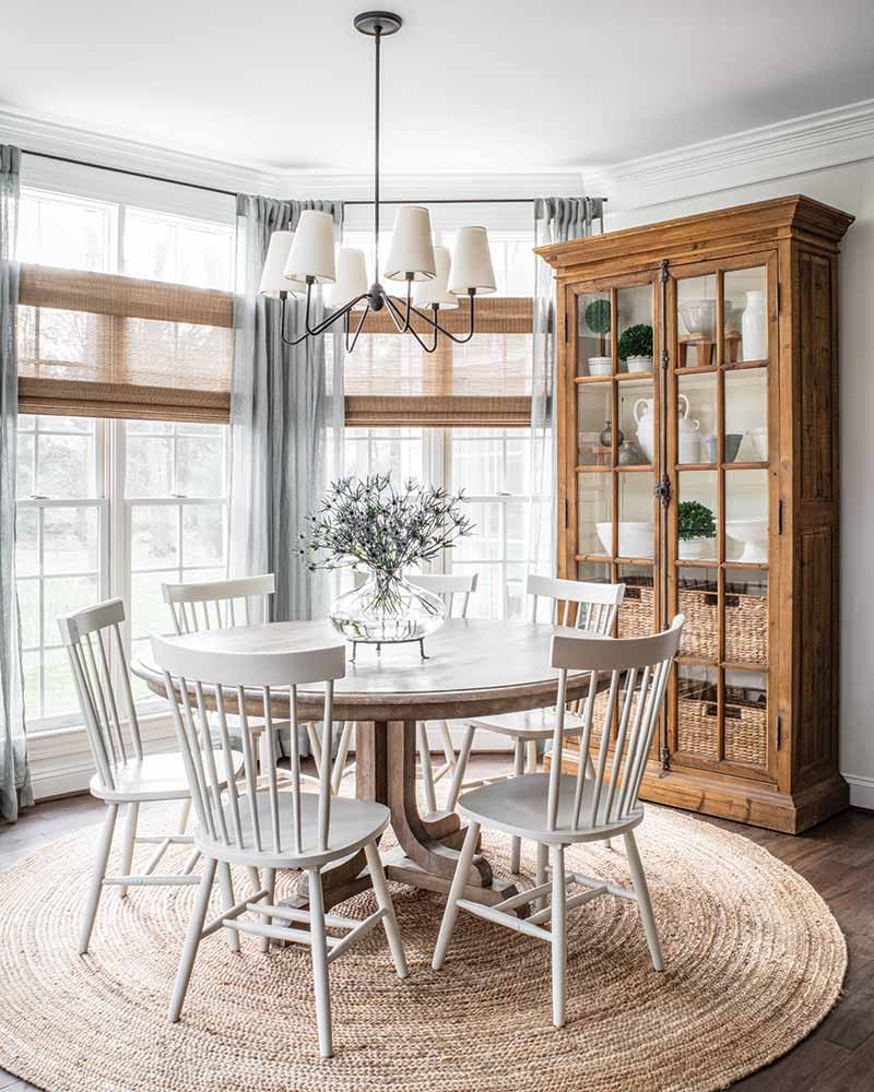 A breakfast nook with a round table in front of a bay window. 