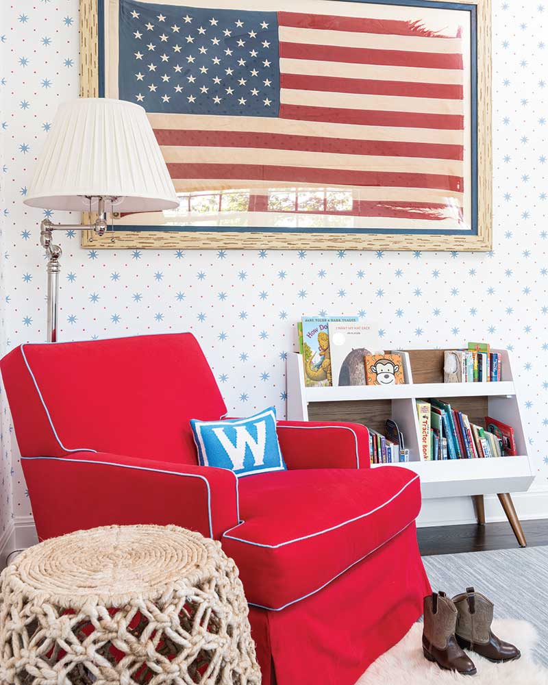 A red armchair in front of a framed American flag.
