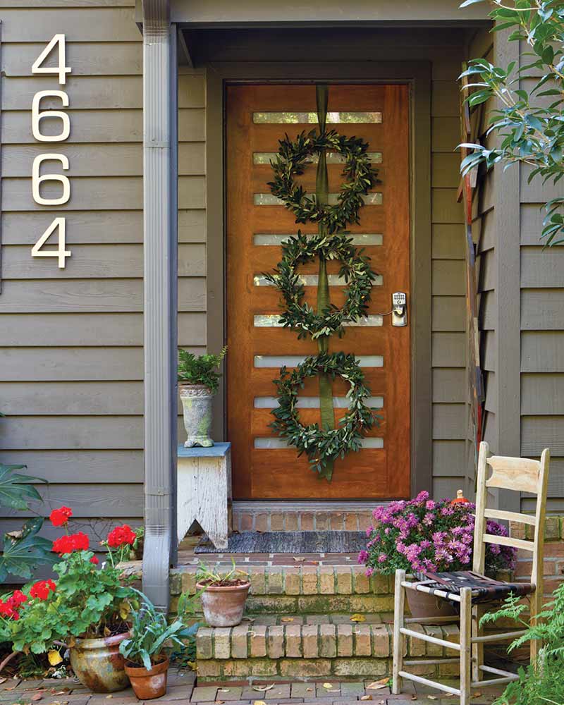 A front door with a hanging trio of boxwood wreaths.