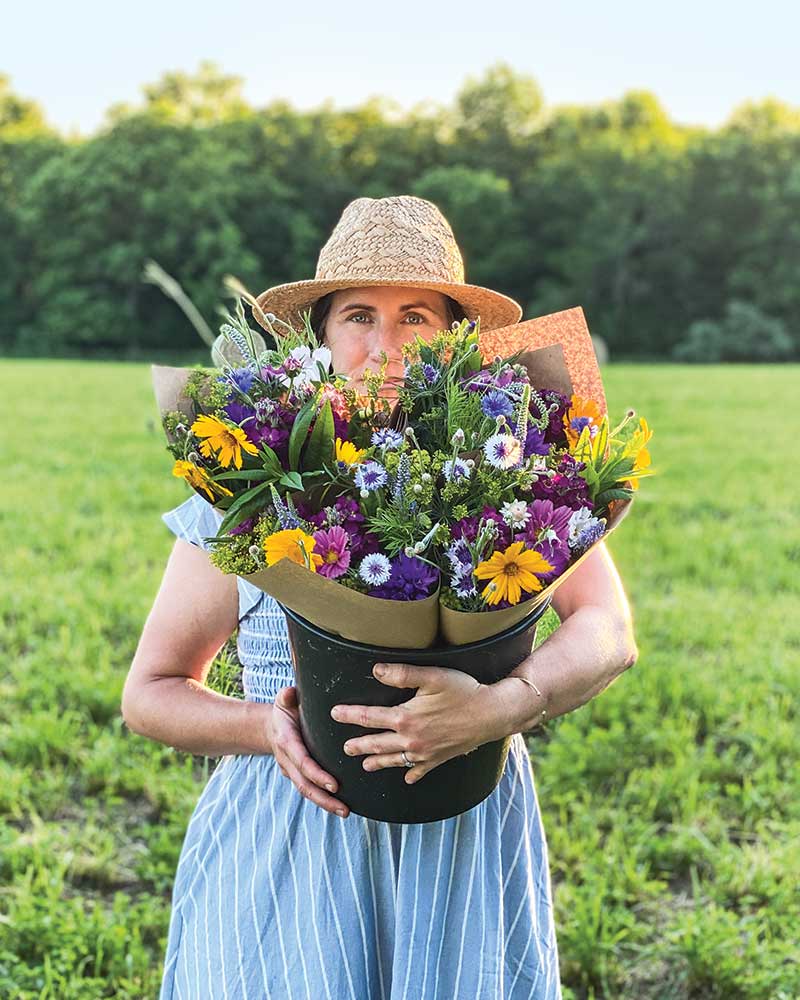 A female holding a bucket of fresh flowers.