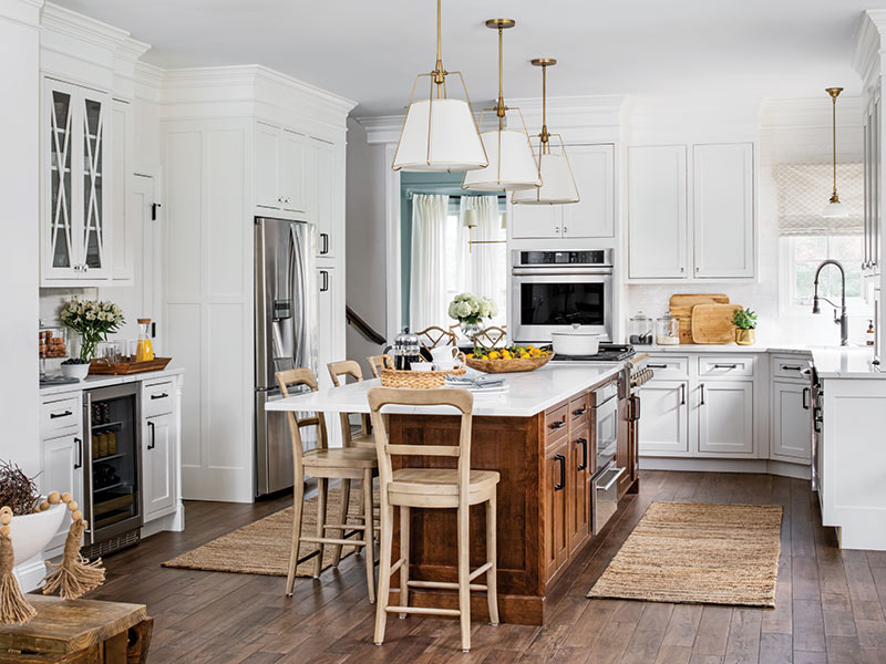 A white kitchen with wood floors and a wood island with a marble countertop.