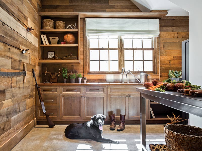 A rustic kitchen with a black lab sitting in the floor.